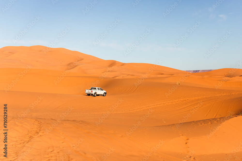 View of an off road vehicle driving across the Sahara desert sand dunes in Merzouga desert, Morocco. View of an off road vehicle driving across the Sahara desert sand dunes in Merzouga desert, Morocco.