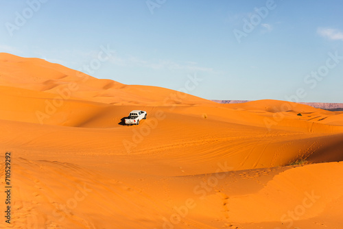 View of an off road vehicle driving across the Sahara desert sand dunes in Merzouga desert, Morocco. photo