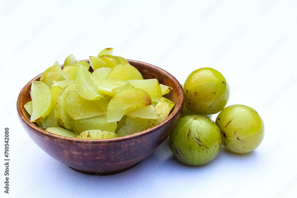 Phyllanthus emblica or Indian gooseberry sliced in a wooden bowl on white background side view Phyllanthus emblica or Indian gooseberry sliced in a wooden bowl on white background side view