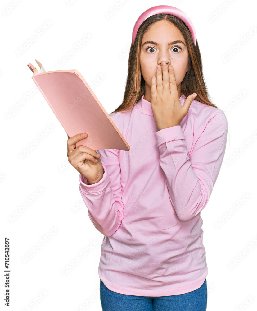 Beautiful brunette little girl reading a book covering mouth with hand, shocked and afraid for mistake. surprised expression Beautiful brunette little girl reading a book covering mouth with hand, shocked and afraid for mistake. surprised expression