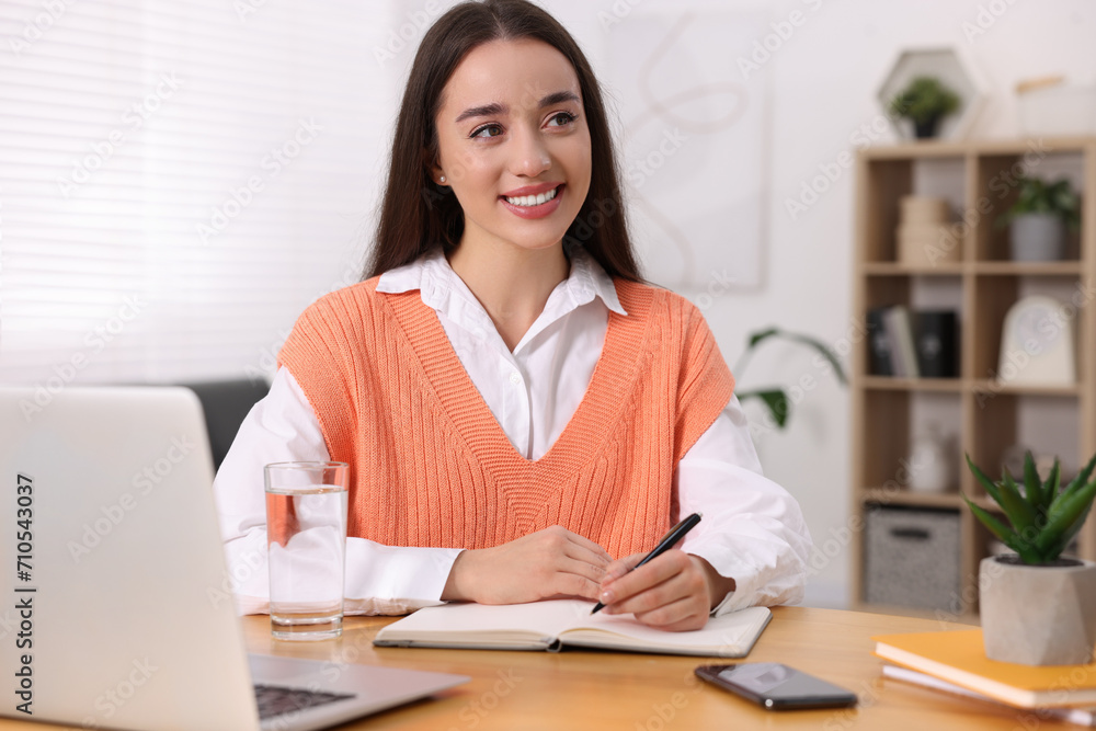Young woman writing in notebook at wooden table indoors Young woman writing in notebook at wooden table indoors