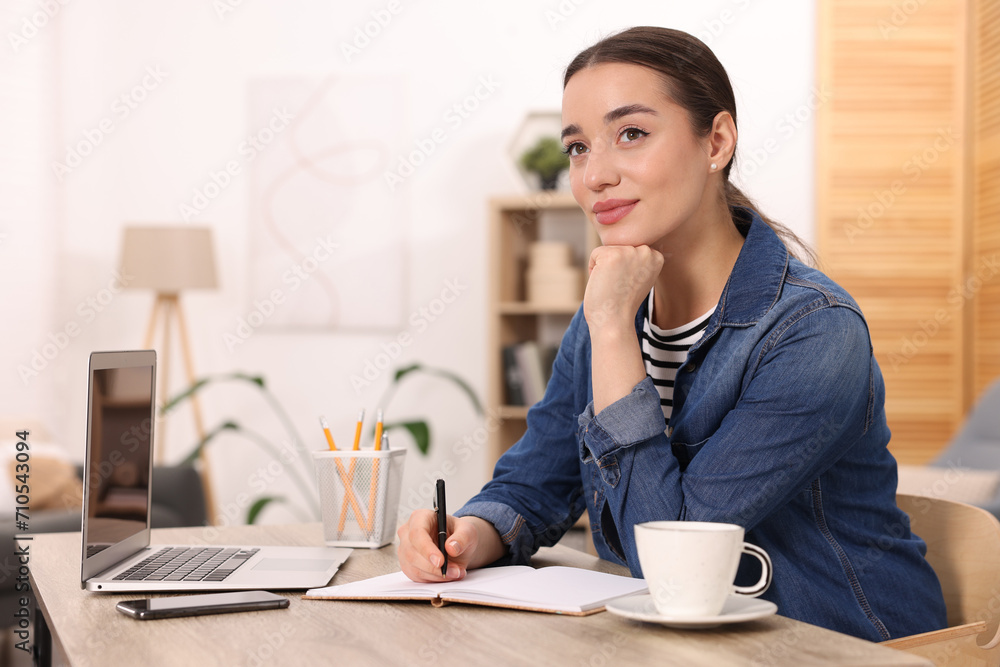Young woman writing in notebook at wooden table indoors Young woman writing in notebook at wooden table indoors