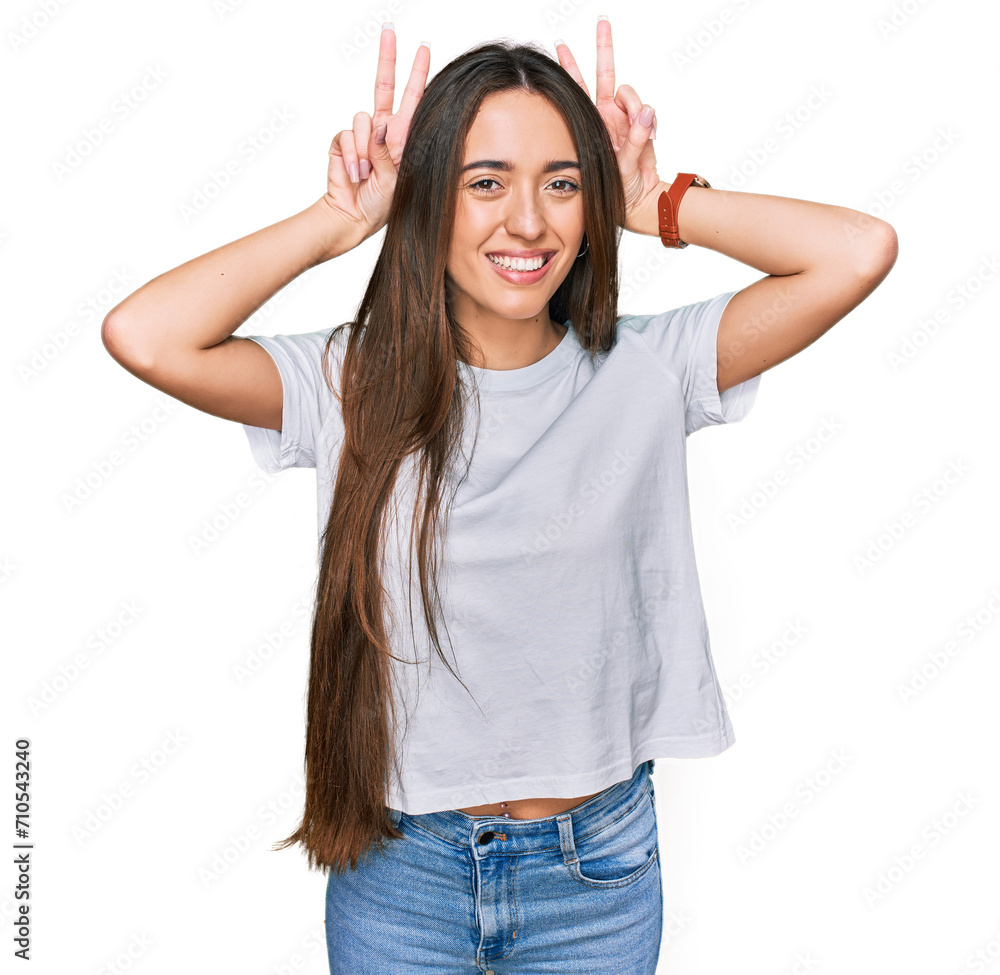 Young hispanic girl wearing casual white t shirt posing funny and crazy with fingers on head as bunny ears, smiling cheerful Young hispanic girl wearing casual white t shirt posing funny and crazy with fingers on head as bunny ears, smiling cheerful
