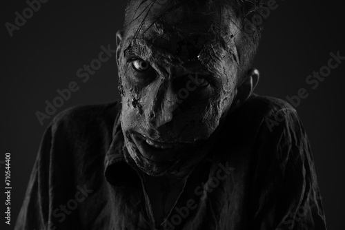 Scary zombie on dark background, black and white effect. Halloween monster