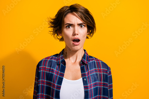 Portrait of astonished dissatisfied girl with bob hair wear plaid shirt astonished staring open mouth isolated on yellow color background