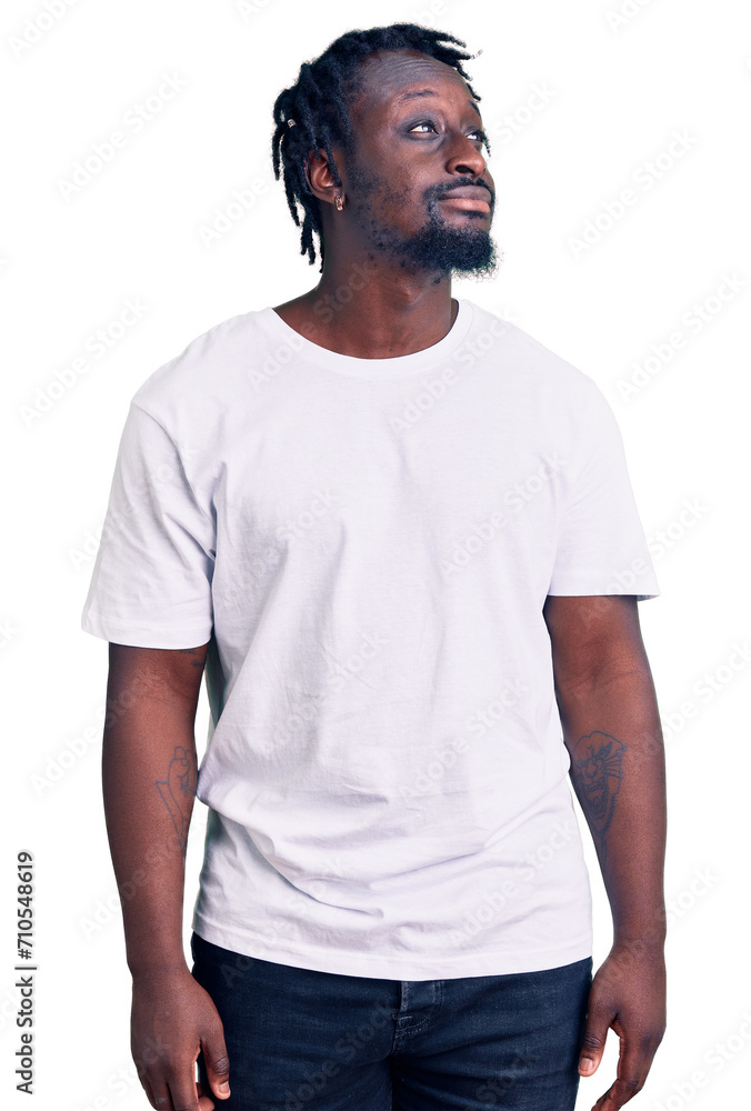 Obraz premium Young african american man with braids wearing casual white tshirt smiling looking to the side and staring away thinking.