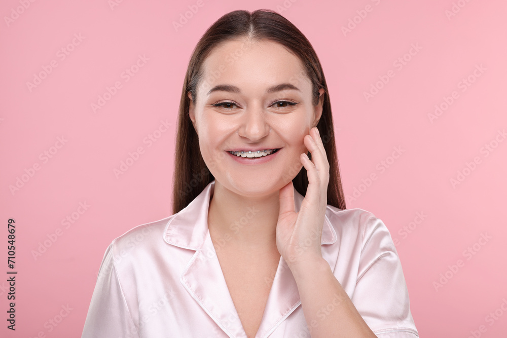 Smiling woman with dental braces on pink background Smiling woman with dental braces on pink background