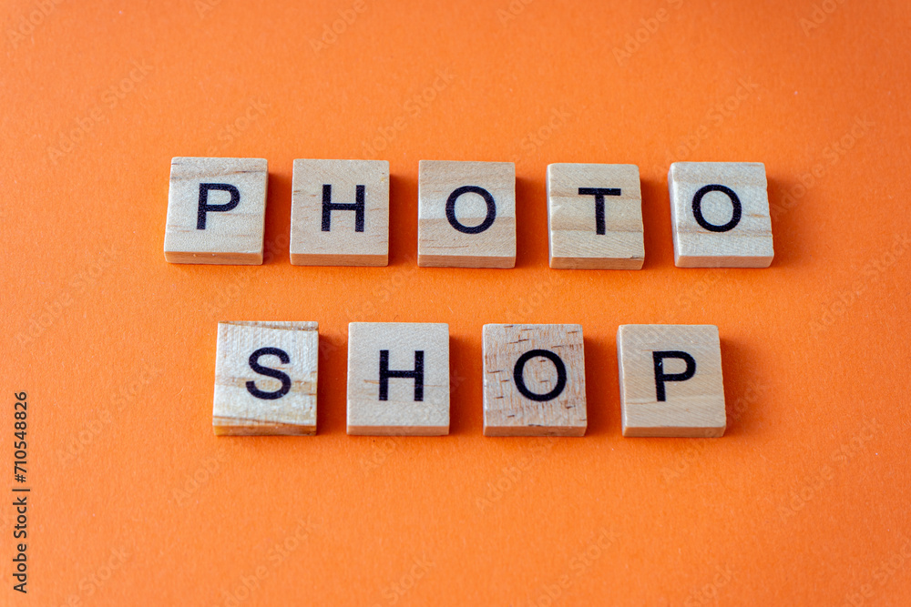 Word photo shop. The phrase is laid out in wooden letters top view. Orange flat lay background Word photo shop. The phrase is laid out in wooden letters top view. Orange flat lay background