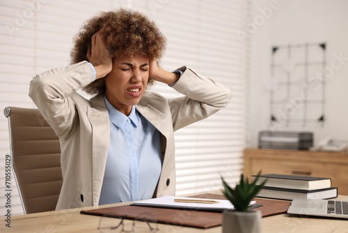 Woman suffering from headache at workplace in office © New Africa