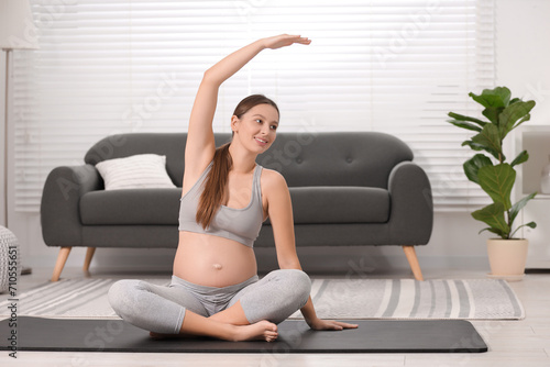 Pregnant woman doing exercises on yoga mat at home