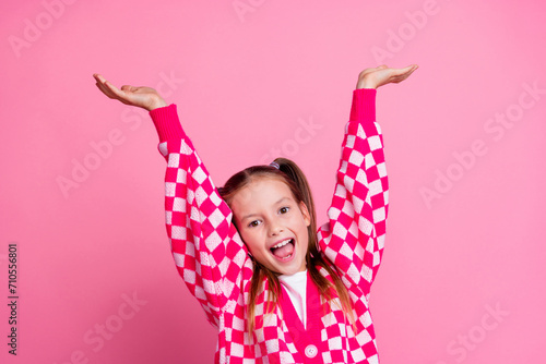 Photo of funny pleasant girl with tails dressed knit cardigan hands up presenting offer empty space isolated on pink color background