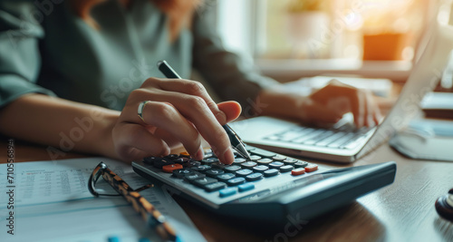 Close-up of a woman's hand using a calculator to calculate finances, working in the office at the table. Finance and economics or business concept. photo
