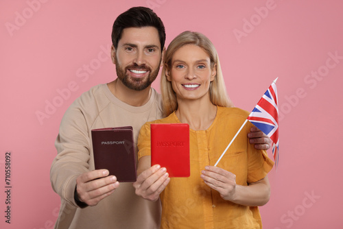 Immigration. Happy couple with passports and flag of United Kingdom on pink background photo