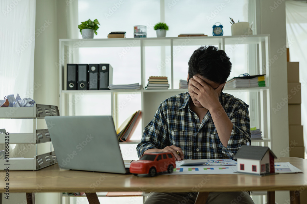 A young Asian man is stressed about bills, car payments, house payments, and holds his head in his hands as he looks at the bills. Confused about financial information or worried about spending money A young Asian man is stressed about bills, car payments, house payments, and holds his head in his hands as he looks at the bills. Confused about financial information or worried about spending money