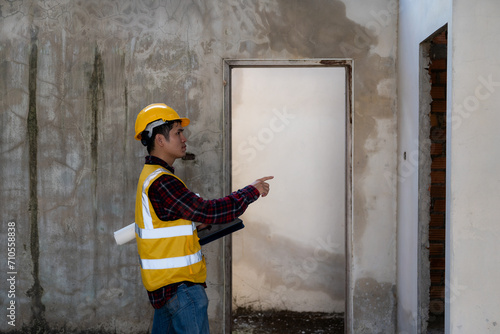 Young man engineer or construction supervisor inspecting work on project, architect wearing helmet and vest doing inspection and inspection. Quality of work done