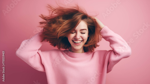 Caucasian woman wearing a sweater on a pink background.