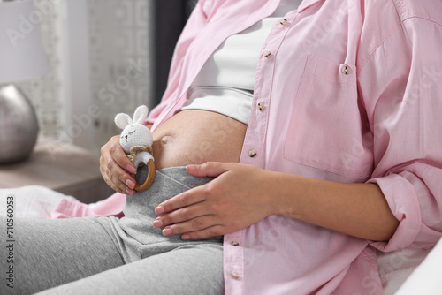 Pregnant woman with bunny toy lying on bed indoors  closeup