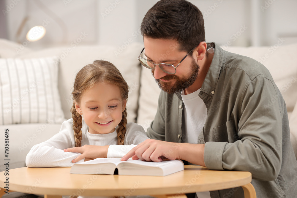Girl and her godparent reading Bible together at table in room Girl and her godparent reading Bible together at table in room