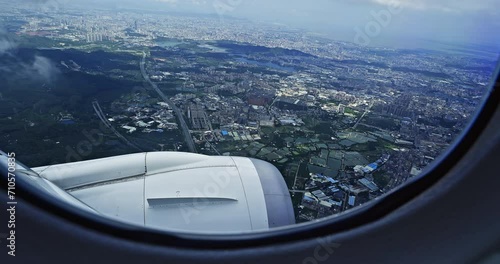 Airplane flight. Wing of an airplane flying above the city skyline. View from the window of the plane. The plane is descending over the city. Traveling by air. 4K real time video.