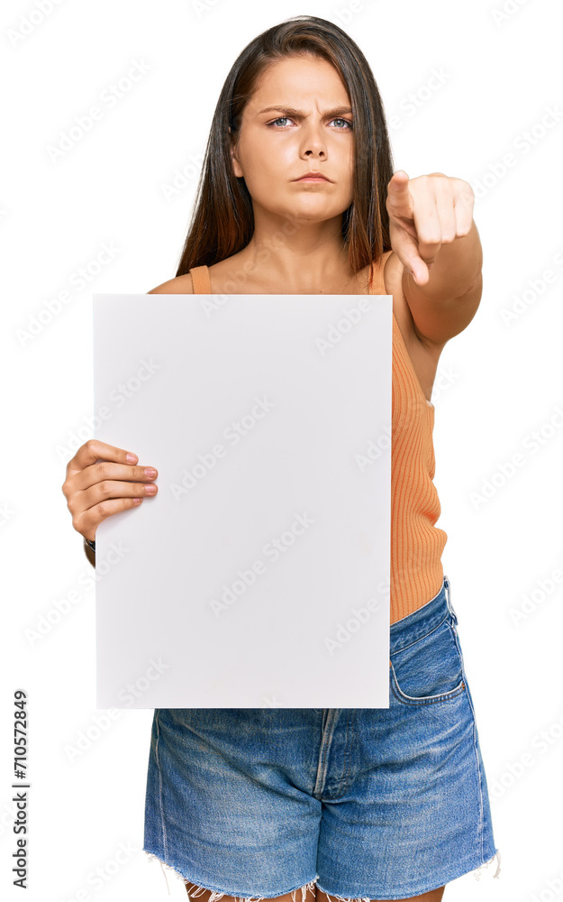 Young caucasian woman holding blank empty banner pointing with finger to the camera and to you, confident gesture looking serious Young caucasian woman holding blank empty banner pointing with finger to the camera and to you, confident gesture looking serious