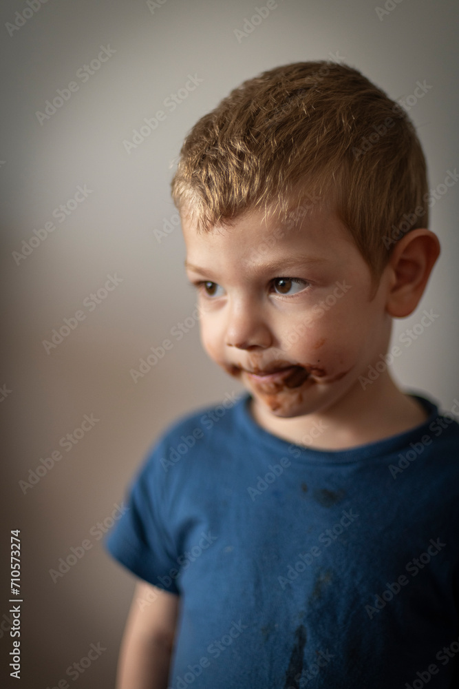Retrato de niño rubio haciendo muecas con la boca sucia de chocolate Retrato de niño rubio haciendo muecas con la boca sucia de chocolate