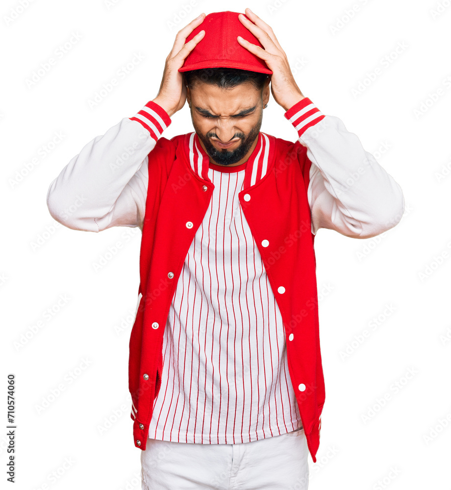 Young man with beard wearing baseball uniform suffering from headache desperate and stressed because pain and migraine. hands on head. Young man with beard wearing baseball uniform suffering from headache desperate and stressed because pain and migraine. hands on head.