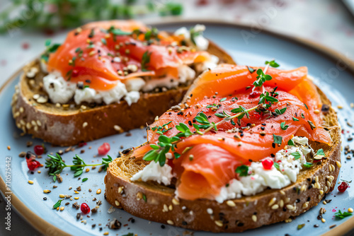 Smoked salmon on toasted bread, garnished with creamy white cheese and fresh green herbs. The toast is placed on a blue plate and grey surface.