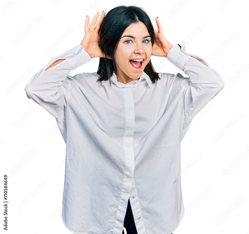 Young brunette woman with blue eyes wearing oversize white shirt smiling cheerful playing peek a boo with hands showing face. surprised and exited Young brunette woman with blue eyes wearing oversize white shirt smiling cheerful playing peek a boo with hands showing face. surprised and exited