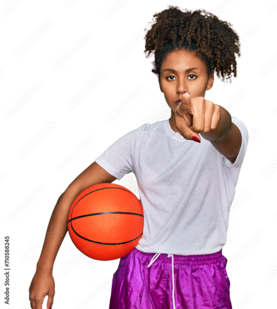 Young african american girl playing baseball holding bat and ball pointing with finger to the camera and to you, confident gesture looking serious