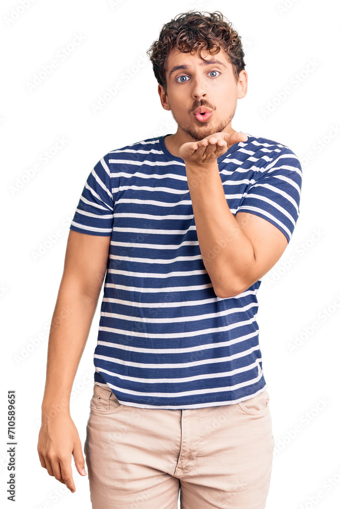 Young handsome man with curly hair wearing casual clothes looking at the camera blowing a kiss with hand on air being lovely and sexy. love expression. Young handsome man with curly hair wearing casual clothes looking at the camera blowing a kiss with hand on air being lovely and sexy. love expression.