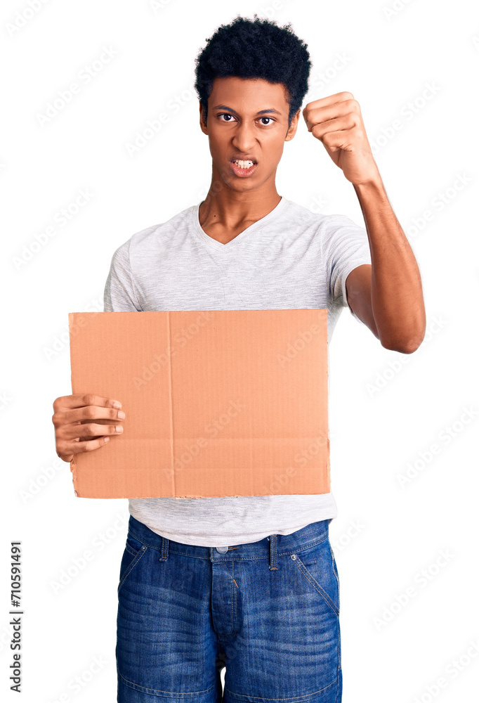 Young african american man holding banner cardboard annoyed and frustrated shouting with anger, yelling crazy with anger and hand raised Young african american man holding banner cardboard annoyed and frustrated shouting with anger, yelling crazy with anger and hand raised