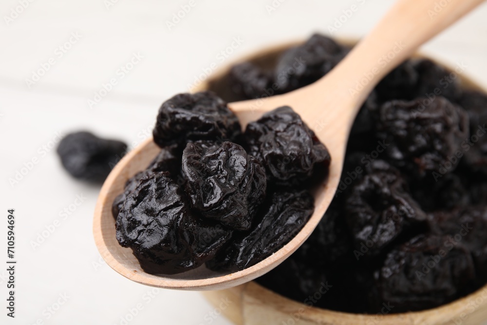 Bowl and spoon with sweet dried prunes on white table, closeup Bowl and spoon with sweet dried prunes on white table, closeup