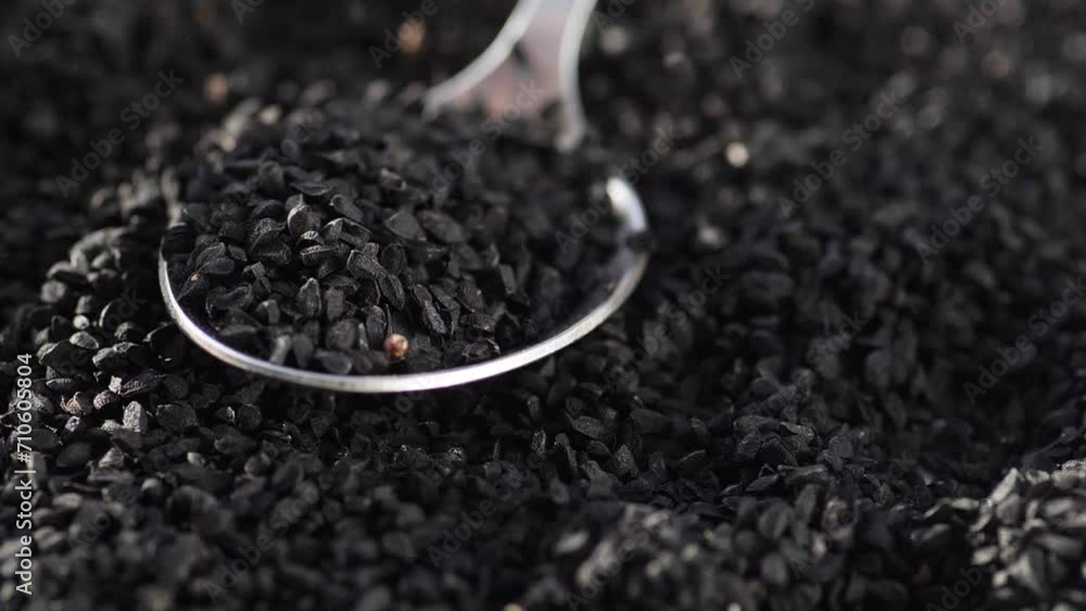 black cumin seeds falling into a spoon in a pile. slow motion. black cumin seeds in cooking black cumin seeds falling into a spoon in a pile. slow motion. black cumin seeds in cooking