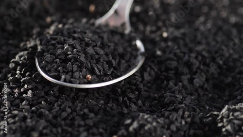 black cumin seeds falling into a spoon in a pile. slow motion. black cumin seeds in cooking photo