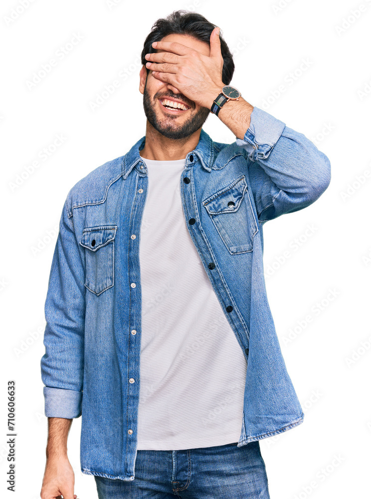 Young hispanic man wearing casual clothes smiling and laughing with hand on face covering eyes for surprise. blind concept. Young hispanic man wearing casual clothes smiling and laughing with hand on face covering eyes for surprise. blind concept.