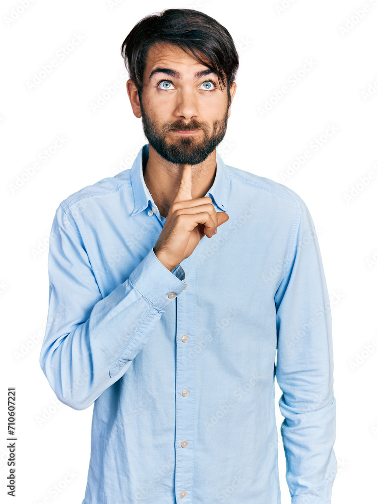 Hispanic man with blue eyes wearing business shirt thinking concentrated about doubt with finger on chin and looking up wondering Hispanic man with blue eyes wearing business shirt thinking concentrated about doubt with finger on chin and looking up wondering