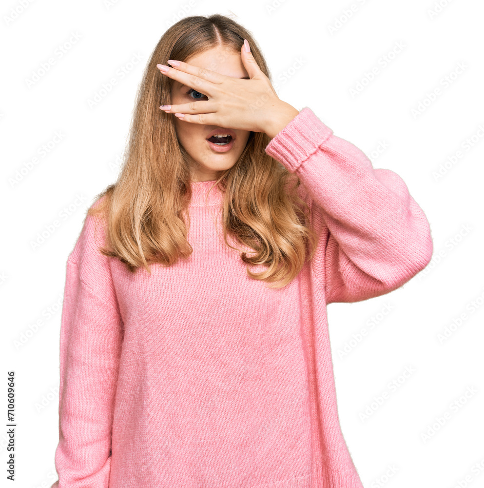 Beautiful young caucasian girl wearing casual winter sweater peeking in shock covering face and eyes with hand, looking through fingers with embarrassed expression. Beautiful young caucasian girl wearing casual winter sweater peeking in shock covering face and eyes with hand, looking through fingers with embarrassed expression.