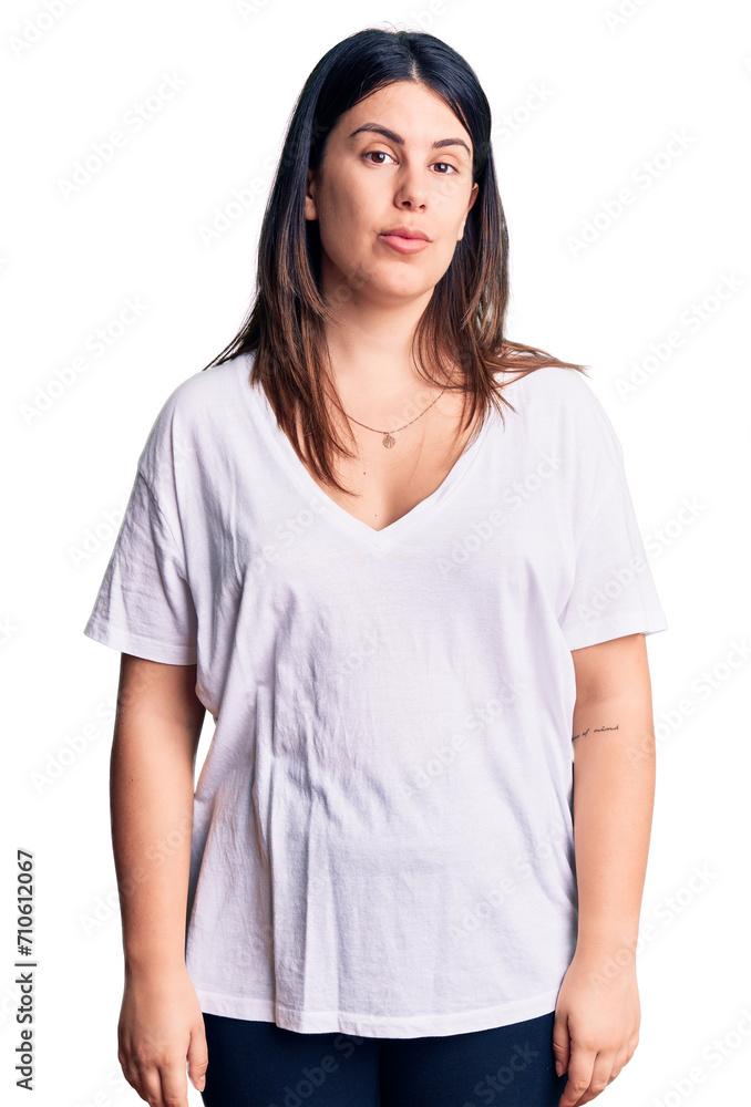 Young beautiful brunette woman wearing casual t-shirt relaxed with serious expression on face. simple and natural looking at the camera. Young beautiful brunette woman wearing casual t-shirt relaxed with serious expression on face. simple and natural looking at the camera.