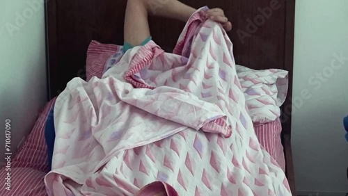 Teenage boy lying in bed under the sheets.