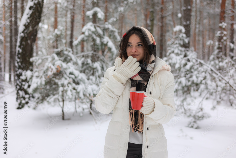Portrait of a young pretty girl in a winter snowy forest. Happy girl in winter scenery, holding a red cup in her hand. Portret młodej, ładnej, uśmiechniętej dziewczyny w zimowym,śnieżnym lesie. Portrait of a young pretty girl in a winter snowy forest. Happy girl in winter scenery, holding a red cup in her hand. Portret młodej, ładnej, uśmiechniętej dziewczyny w zimowym,śnieżnym lesie.