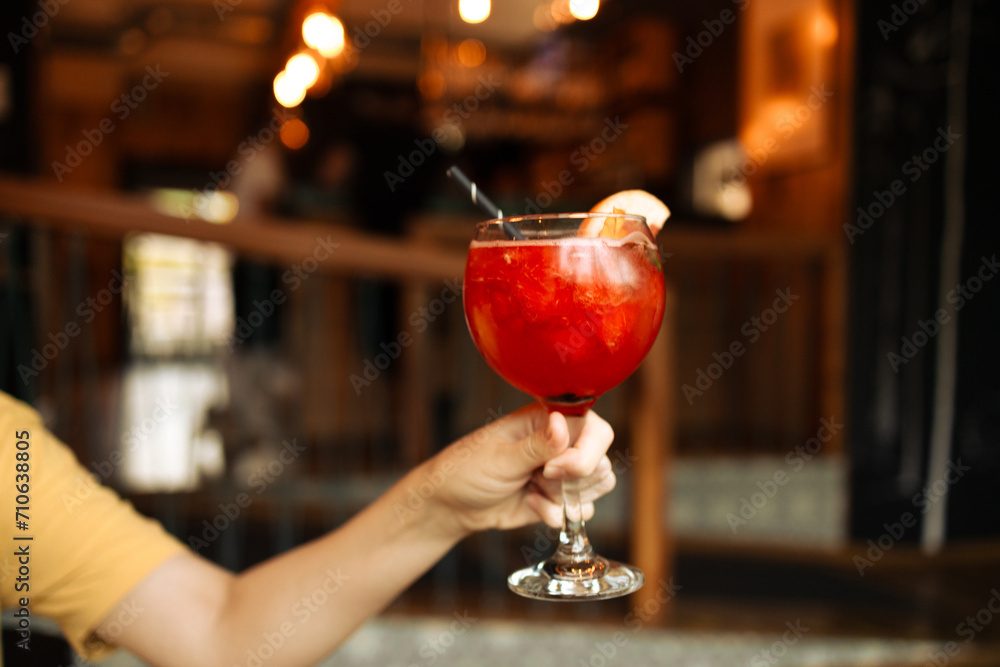 Popular bar summer ice alcoholic cocktails. Aperol Spritz and strawberry basil Margarita in glasses in woman hand at city cafe. High quality photo