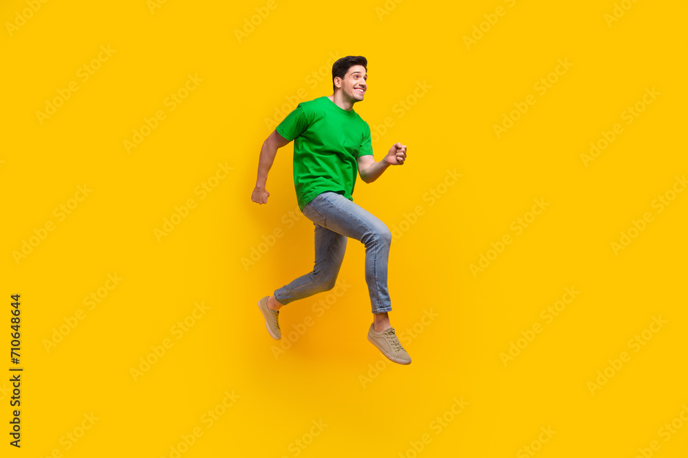 Full length photo of optimistic pleasant man dressed green t-shirt look at sale empty space running isolated on yellow color background