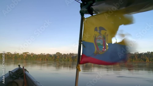 A boat floats down the Rio Napo, Ecuador, in the town of Puerto Francisco de Orellana, also known as El Coca, in South America. Torn Ecuadorian flag on motorboat. photo