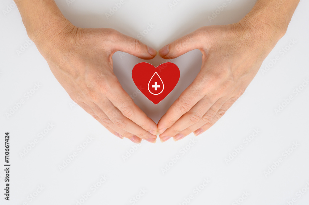 Obraz premium Donor blood collection concept. Blood donation. Red heart with a drop of blood in female hands