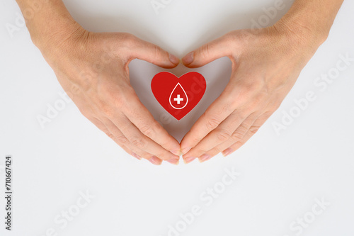 Donor blood collection concept. Blood donation. Red heart with a drop of blood in female hands