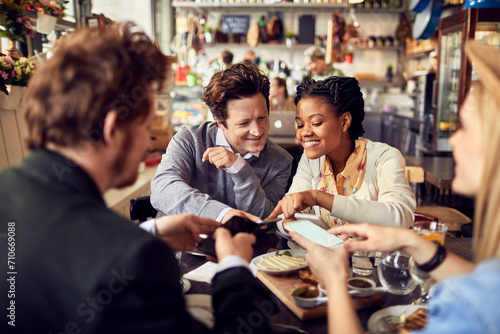 Diverse young people using smartphone during lunch at restaurant photo