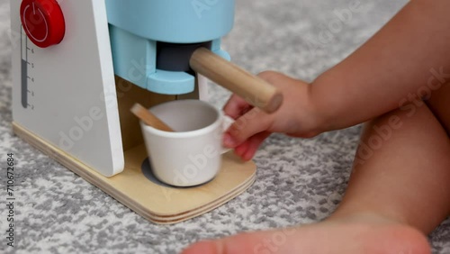adorable baby playing with toy espresso machine. kid child putting cup, coffee, pretend to drink. coffee maker made from eco wood, safe creative roll play toys.boy sitting on floor 4k photo