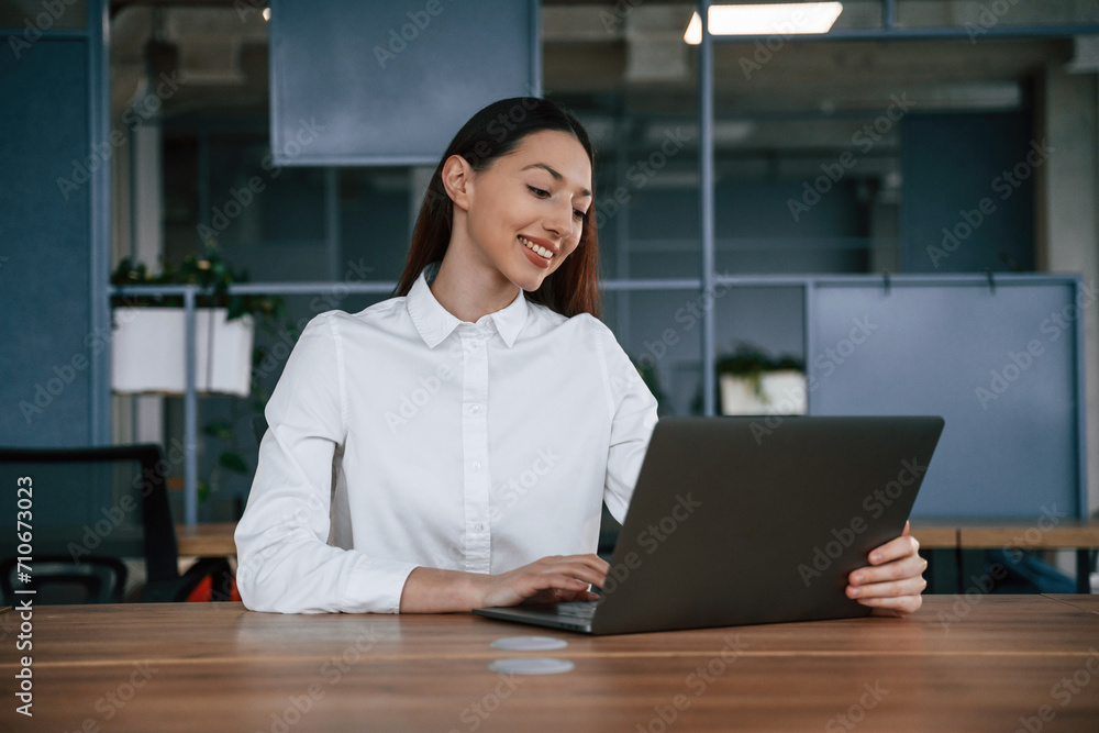 Working by using laptop. Businesswoman is indoors in the office Working by using laptop. Businesswoman is indoors in the office