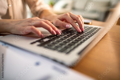 Close-up of woman's hands typing on laptop keyboard