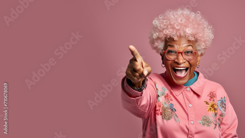 Happy senior afro woman points her finger at copy space for promotion photo